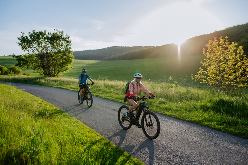 Active,Senior,Couple,Riding,Electric,Bicycles,On,Road,At,Summer