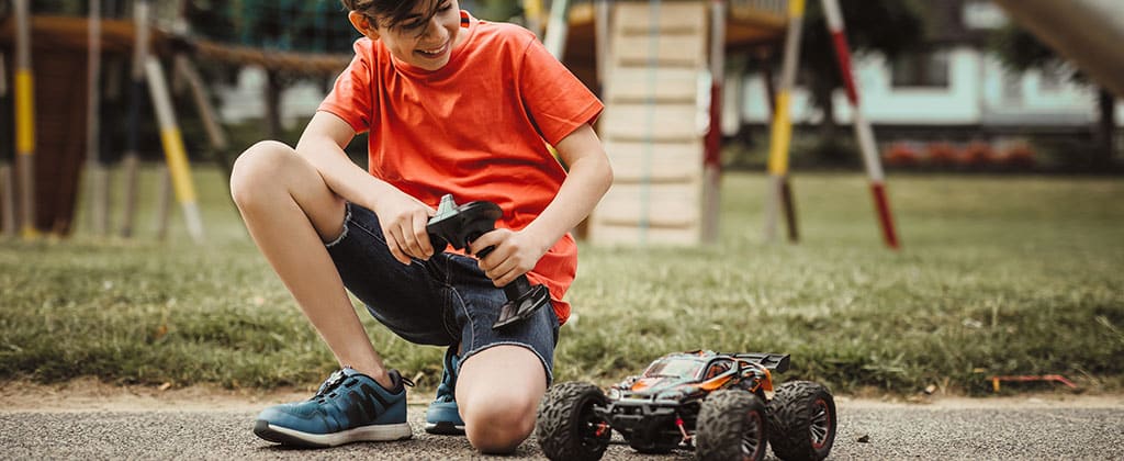 teen boy with electric remote control car toy play outdoor on si