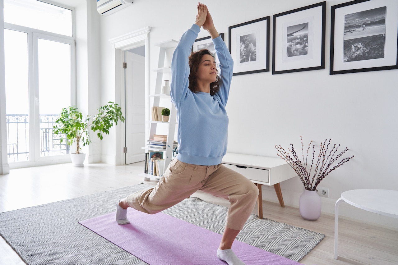 Fit healthy young woman doing yoga warrior exercise standing at home. Fit healthy young woman doing yoga warrior exercise standing at home.