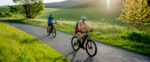 Active,Senior,Couple,Riding,Electric,Bicycles,On,Road,At,Summer
